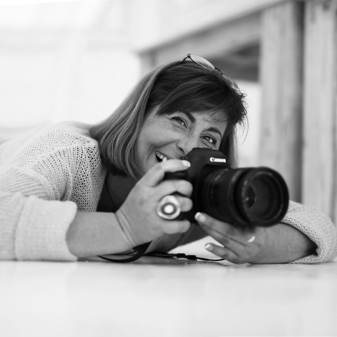 Black and White profile photo of a woman holding a DSLR camera